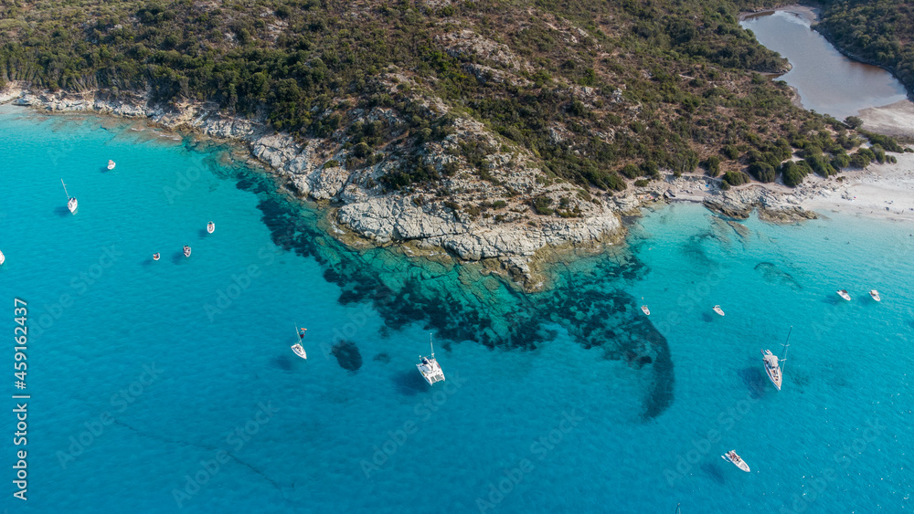 Aerial view of Loto Beach in the Agriates Desert northwest of Saint Florent near the Cap Corse, Corsica, France -Leisure boats moored in azure waters by a rocky shoreline in the Mediterranean Sea Aerial view of Loto Beach in the Agriates Desert northwest of Saint Florent near the Cap Corse, Corsica, France -Leisure boats moored in azure waters by a rocky shoreline in the Mediterranean Sea