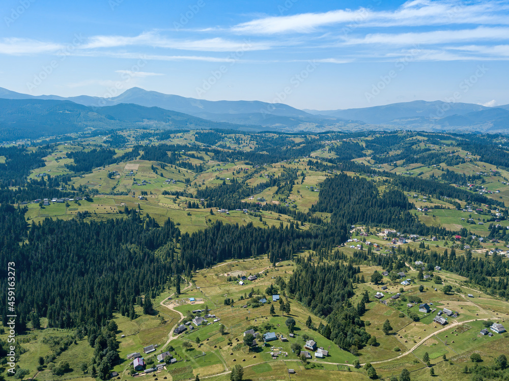 Green mountains of the Ukrainian Carpathians on a sunny summer morning. Coniferous trees on the mountain slopes and green grass. Aerial drone view.