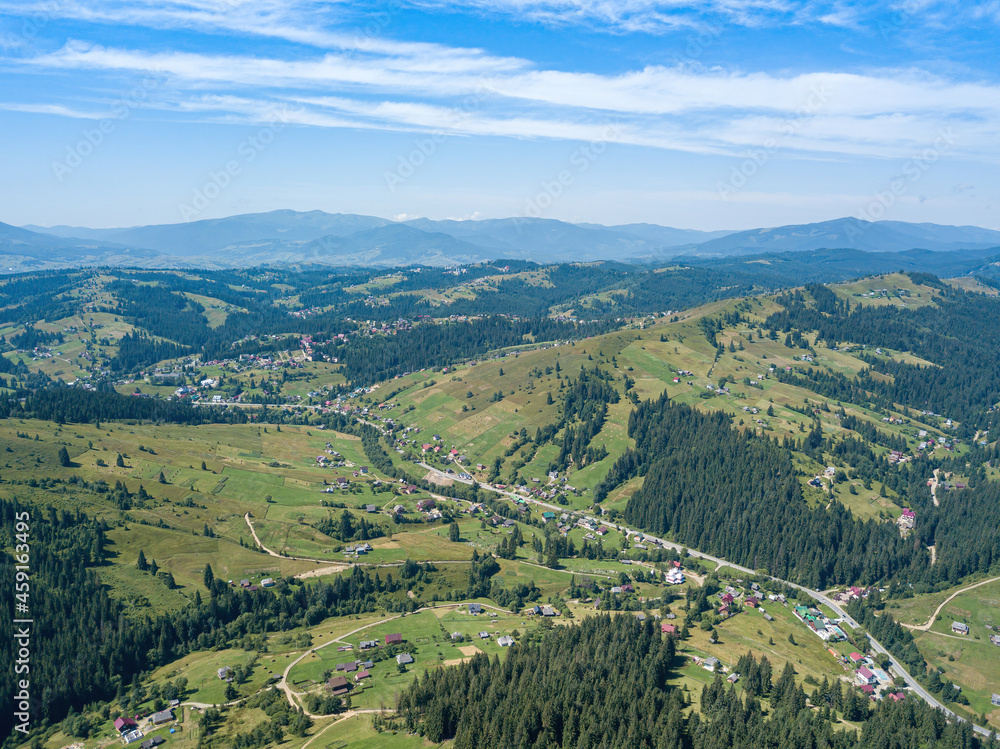 Green mountains of the Ukrainian Carpathians on a sunny summer morning. Coniferous trees on the mountain slopes and green grass. Aerial drone view.