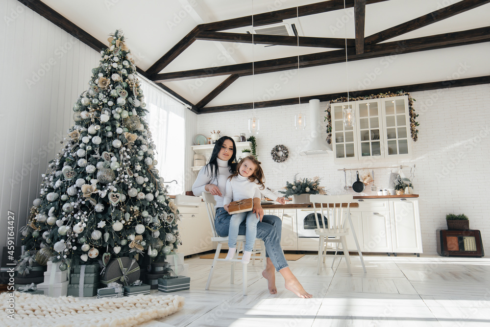 Obraz premium Mom with a little girl unpack gifts. Holiday.