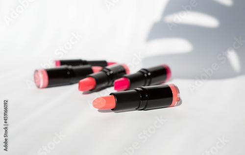 colored bright lipstick on a white background with leaf shadows