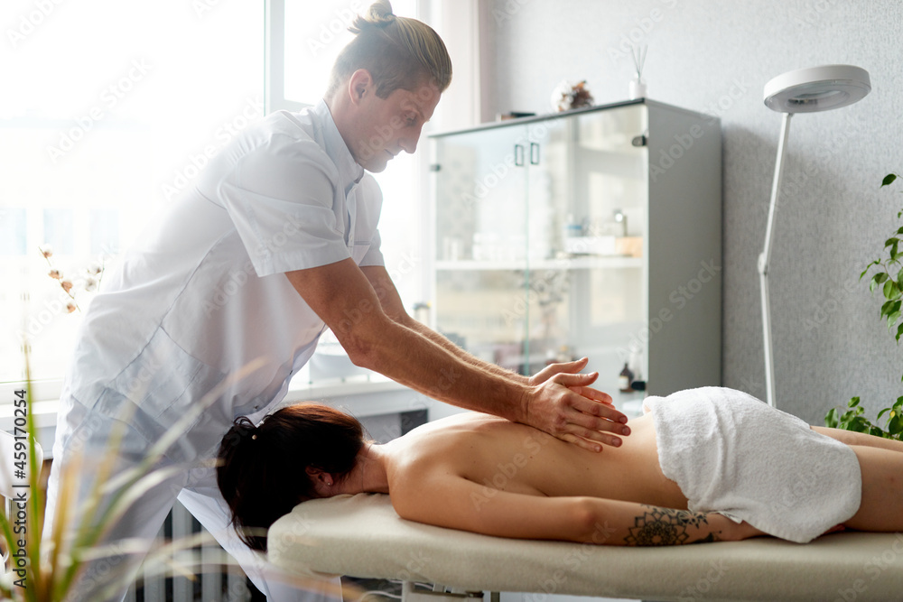 Obraz premium A professional therapist makes a therapeutic massage of the patient's back. Healing body massage at the medical center.