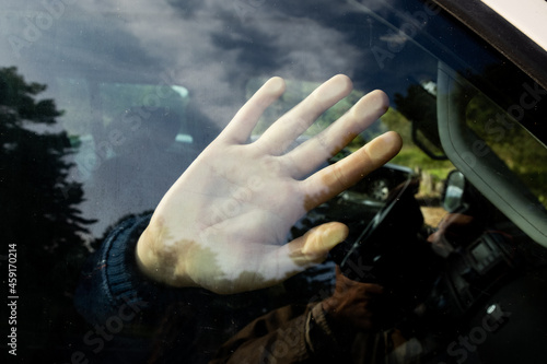 A hand of a child or young woman locked in the car with the reflections of forest trees. Kidnapping, crime and danger theme.
