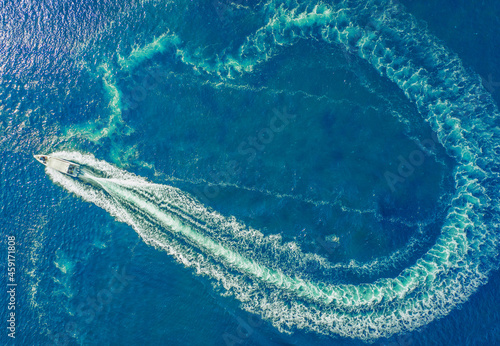 A high-speed boat or yacht maneuvers on the surface of the sea or ocean. Aerial view.