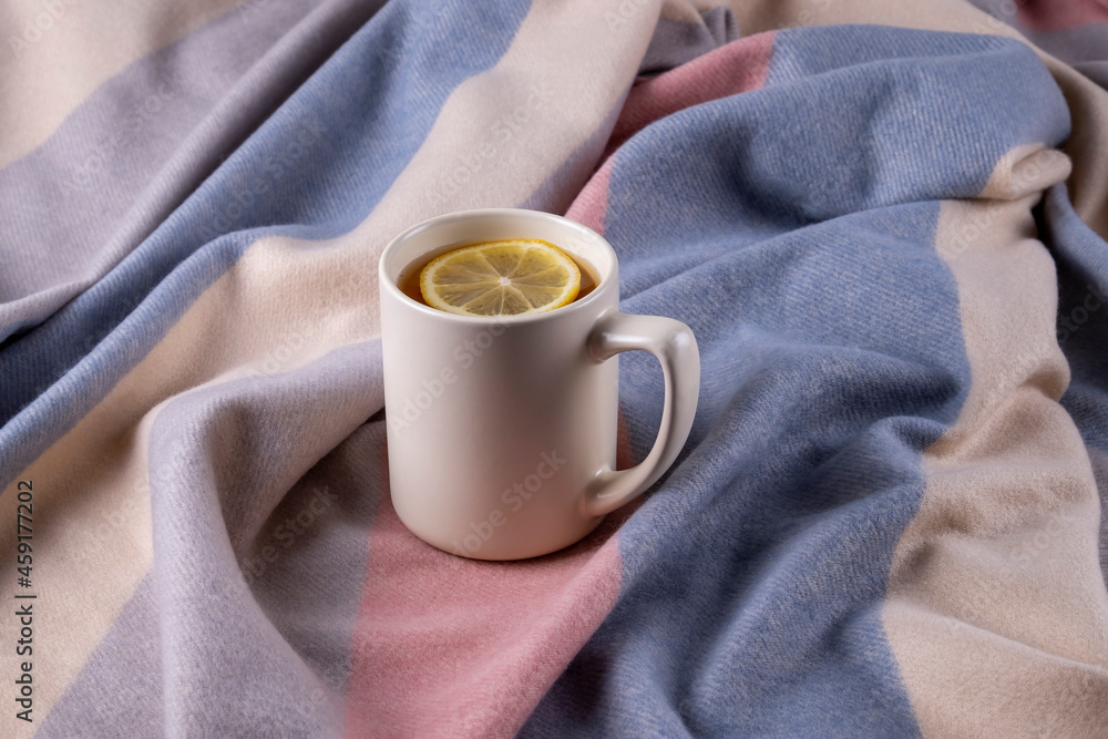 Autumn composition of soft warm scarf in pastel colors and ceramic mug with hot tea with lemon. Selective focus. Autumn composition of soft warm scarf in pastel colors and ceramic mug with hot tea with lemon. Selective focus.