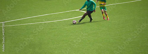 Dois jogadores a jogar futebol e a disputar a posse de bola - equipamentos verde e preto e amarelo e verde - casaco vestido photo