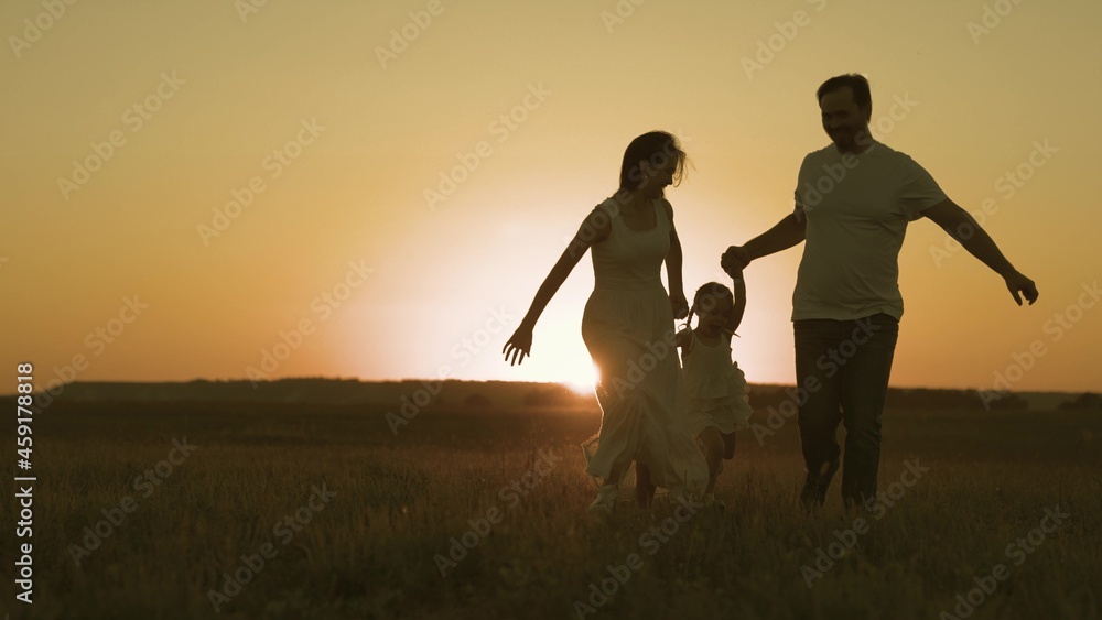 Happy family runs at sunset in sky, mother and father play with child in active jumps, childhood dream of being with mom and dad, having fun with parents outdoors, slow motion, life values concept