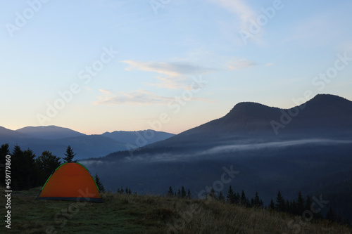 Picturesque mountain landscape with camping tent in morning
