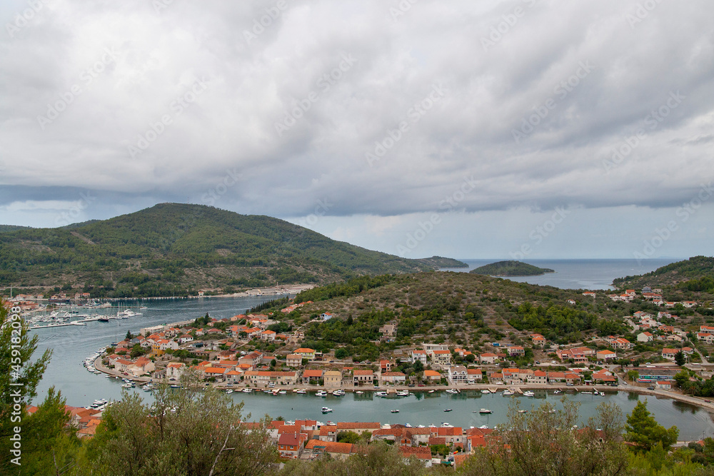 view of the red roofed Mediterranean town on the hill in the sea with stormy clouds