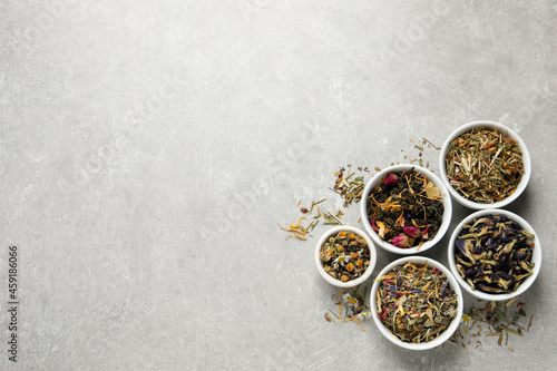 Flat lay composition with different dry teas on light grey table, space for text