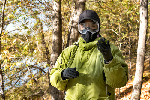 A woman wearing a respirator mask, protective glasses and rubber gloves in the forest at COVID-19 period.