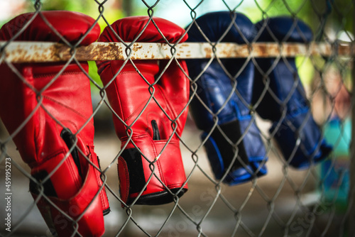 old boxing gloves hang on mesh fence steel