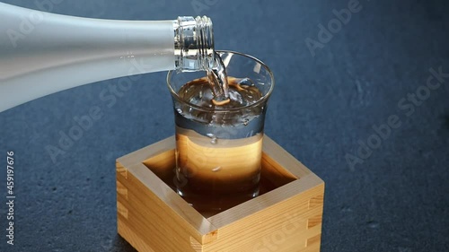 Tokyo,Japan - September 26, 2021: Pouring Sake into a glass inside a wooden measuring box or sake masu. This style is called as Mokkiri or Morikiri or Morikoboshi.
 photo