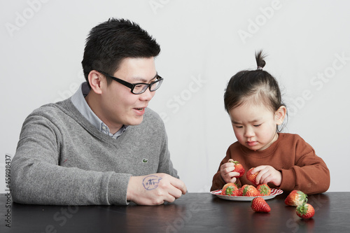 Asian father and daughter eating fruits  indoor white background