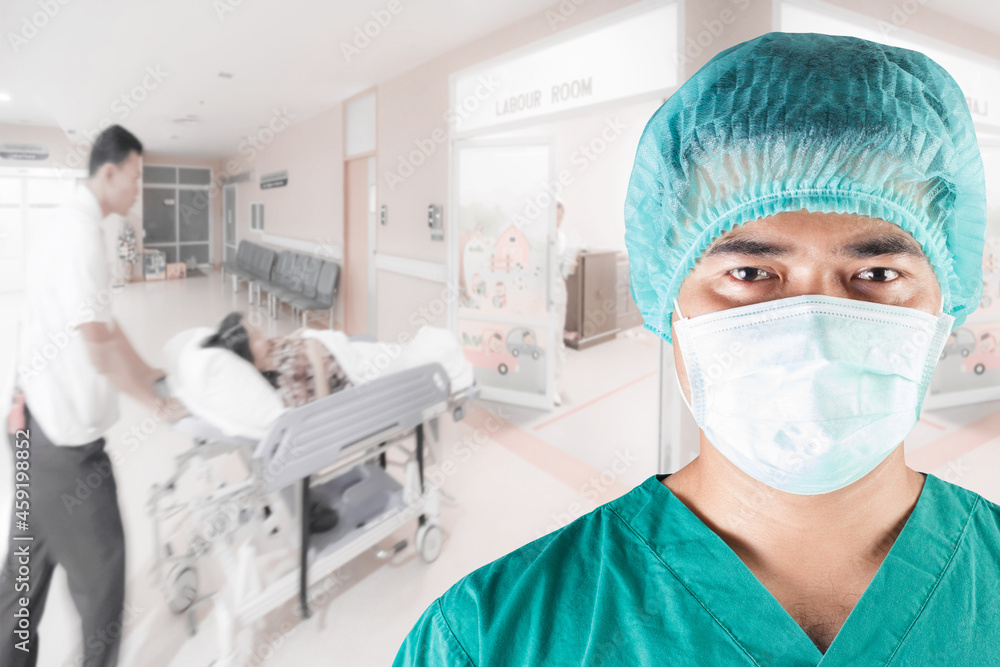 Surgeon looking at camera and medical active staff pushing stretcher gurney bed in labour room of hospital corridor with female patient pregnant in emergency status