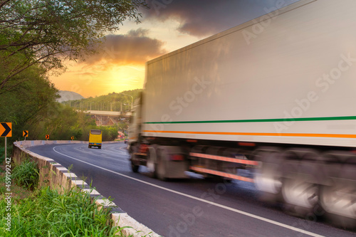 Motion blur of container truck with space for text driving fast on the countryside road with mountain against sunset