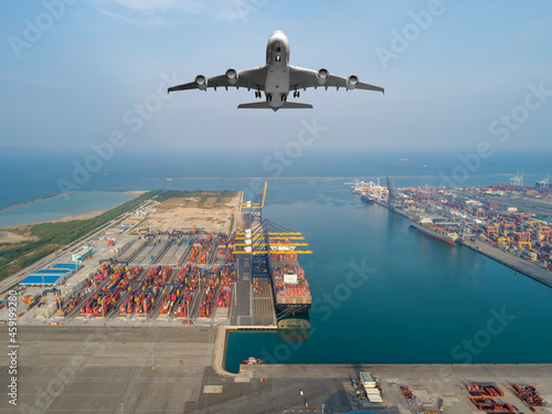 Photography Aerial view of airplane flying above modern ship cargo containers entering to harbor with export and import business and logistics, world wide cargo transportation concept