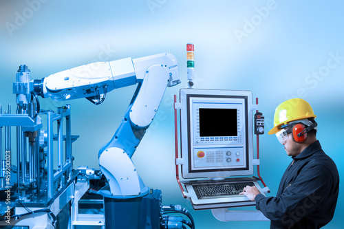 Industry concept and blue tone of engineer use control panel programing automated robot arm in production line of smart factory