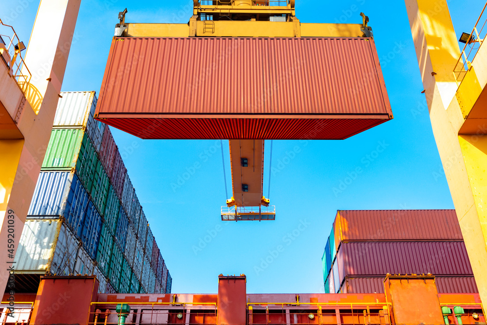 Industrial port crane lift up loading export containers box onboard at port in import and export business logistic industry and transportation concept.