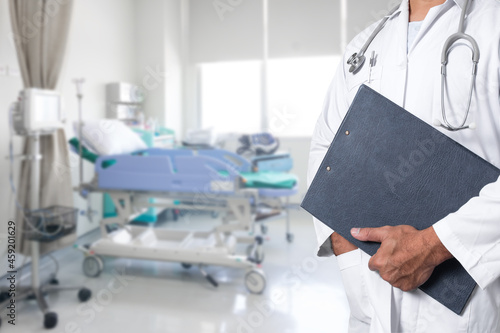 Doctor holding medical records aDoctor holding medical records and folders in the patient Rooms.nd folders with medical staff in the operating room