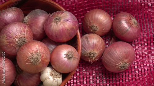 Fresh red onions in a wooden bowl.