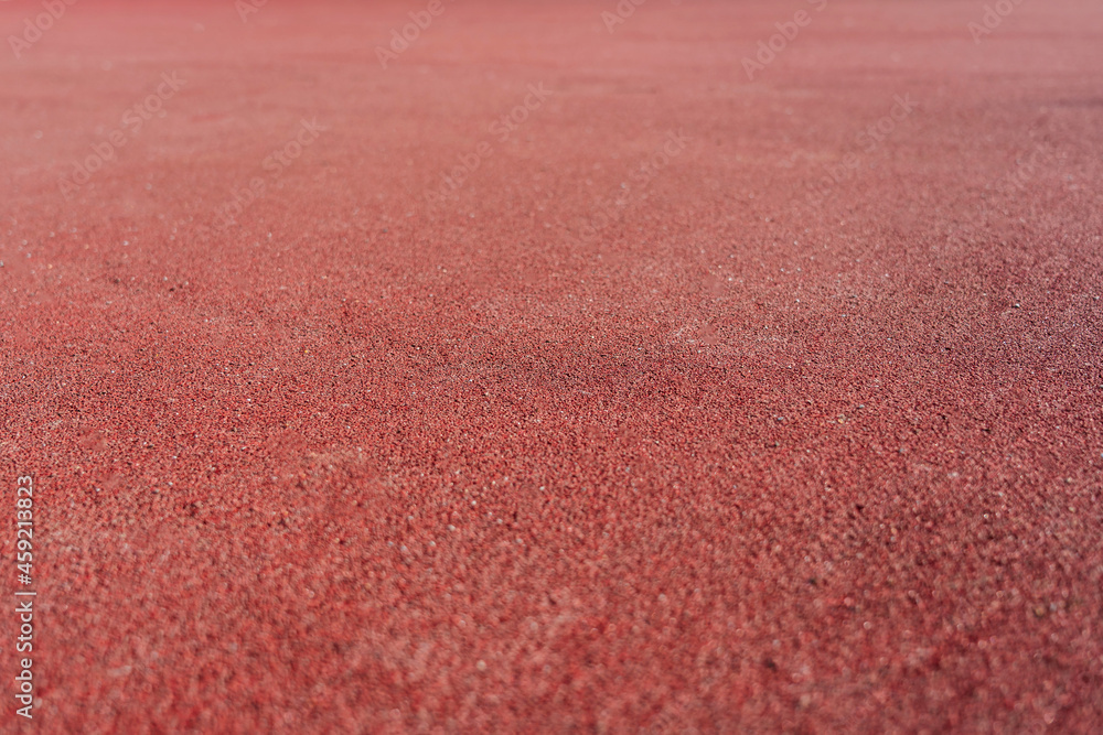 Red rubber coating made of recycled rubber chips on the sports field. Selective focus Red rubber coating made of recycled rubber chips on the sports field. Selective focus