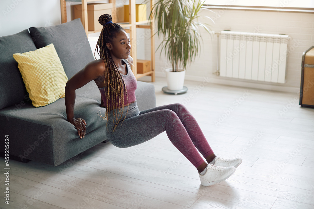 African American sportswoman does triceps dips while leaning on sofa at  home. Stock Photo | Adobe Stock