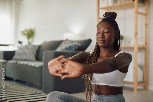 Black female athlete does breathing exercises while practicing Yoga at home.
