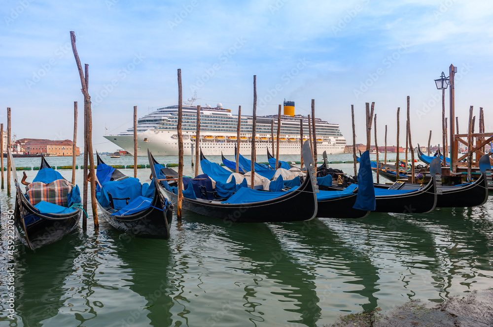 A huge cruise ship passes the Grand Canal in Venice on a spring evening past a gondola stop.