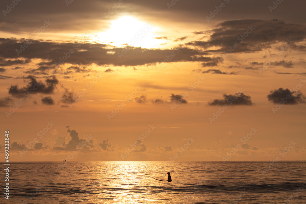 surfer waiting for the waves at sunset very beautiful orange light