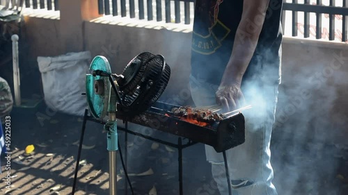 Chicken satay on traditional charcoal fire. satay on fire with smoke and an appetizing look. hands cooking satay on the grill