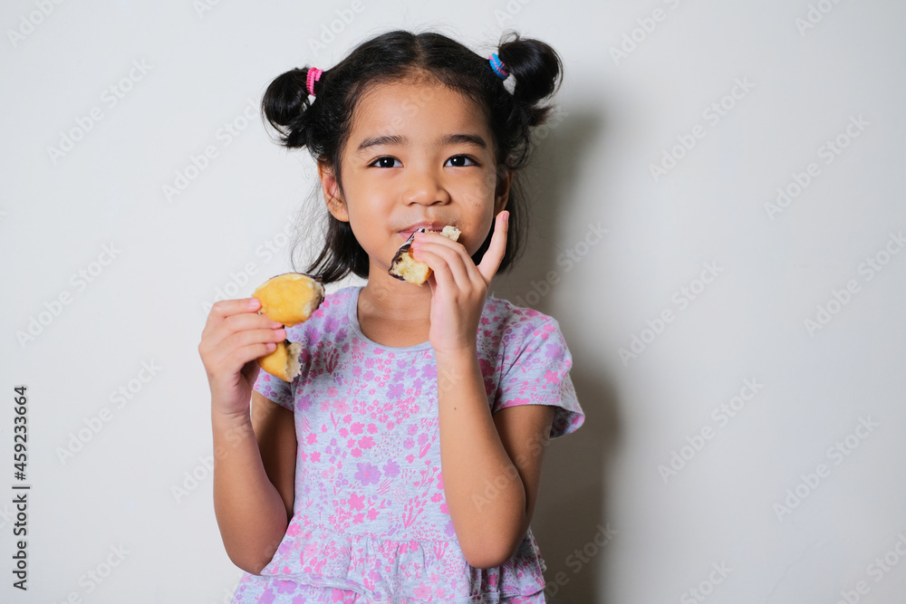 Asian little girl showing happy expression while eating donut Asian little girl showing happy expression while eating donut