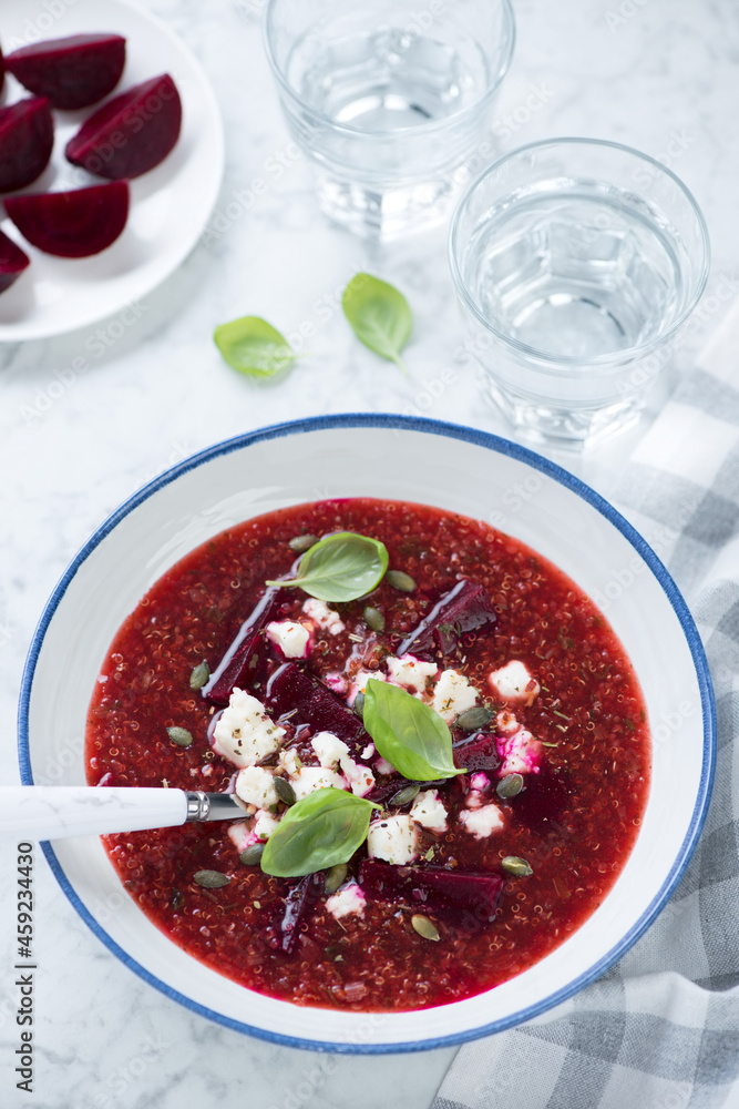 Plate of beetroot and quinoa soup topped with bryndza, vertical shot on a grey marble background, elevated view Plate of beetroot and quinoa soup topped with bryndza, vertical shot on a grey marble background, elevated view