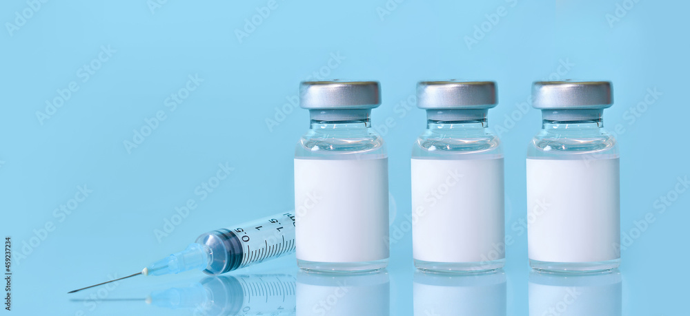 Three vials with a vaccine, a syringe on a blue background.The concept of medicine, healthcare and science.Coronavirus vaccine.Copy space for text..Banner Three vials with a vaccine, a syringe on a blue background.The concept of medicine, healthcare and science.Coronavirus vaccine.Copy space for text..Banner
