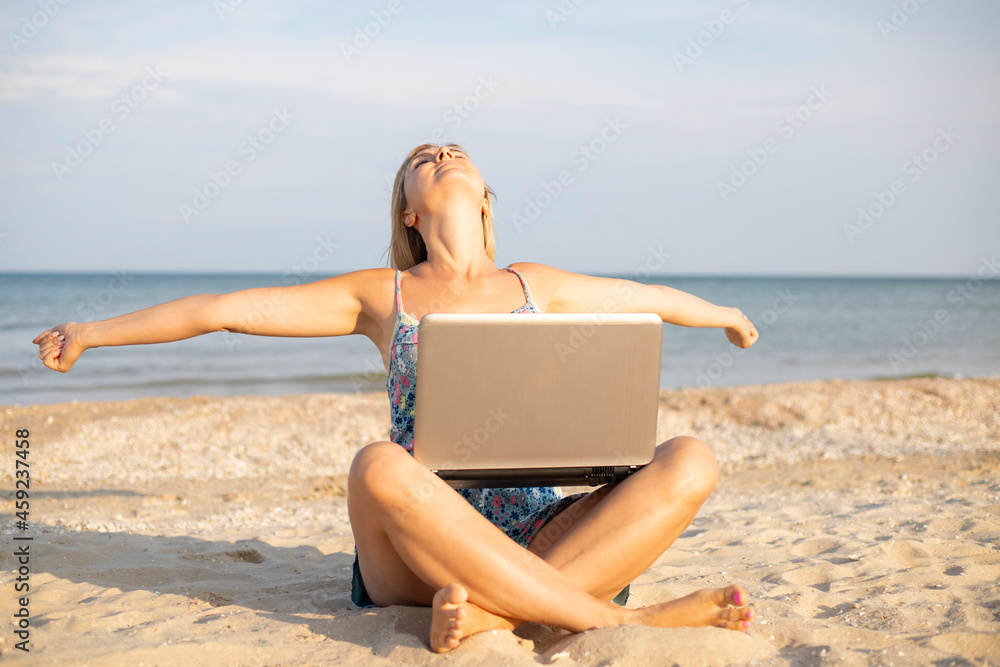Beautiful young woman working with laptop on the tropical beach. Successful person concept