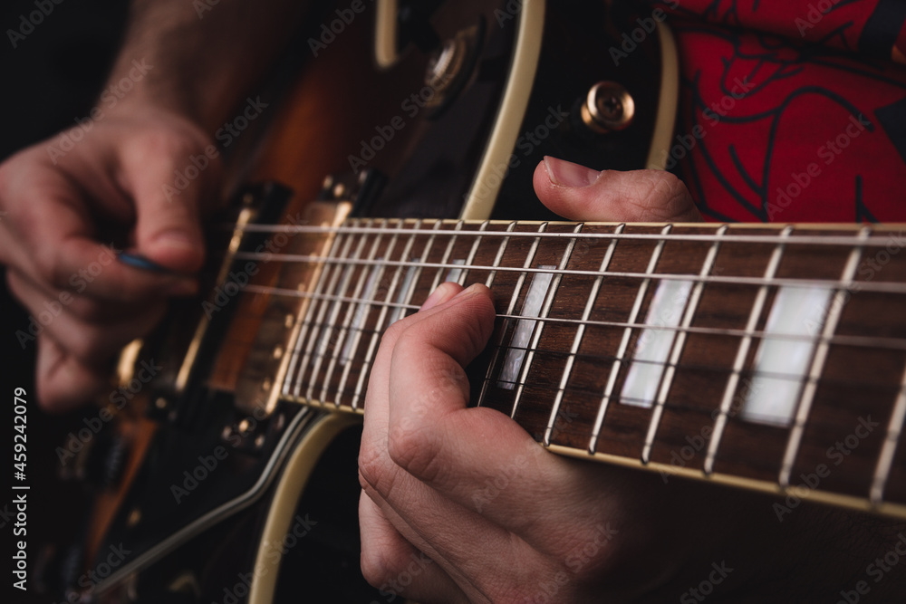 Fototapeta premium Person plucking the strings on the frets of an electric guitar. Selective focus. Copy space.