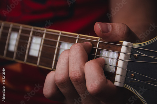 Person plucking the strings on the frets of an electric guitar. Selective focus. Copy space.