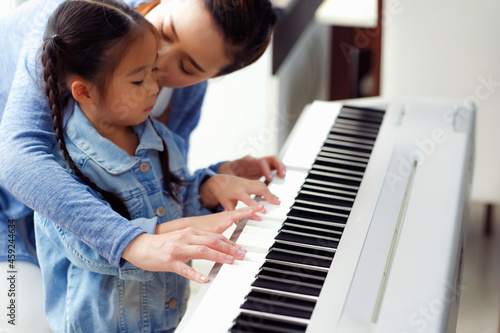 Single mom and daughter playing music with electric piano