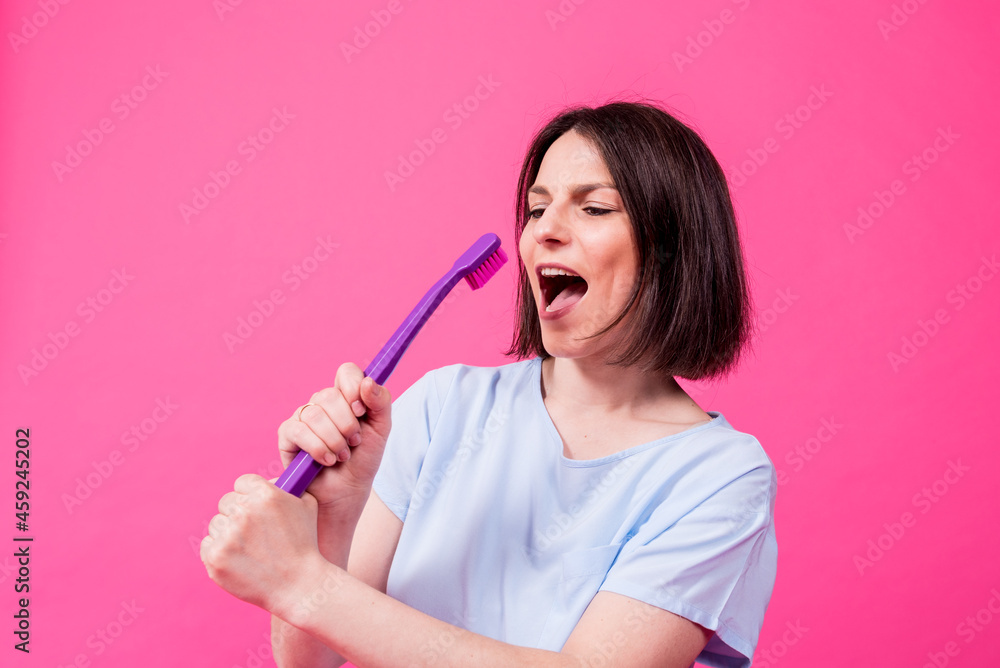 Beautiful happy young woman with big toothbrush on blank pink background Beautiful happy young woman with big toothbrush on blank pink background