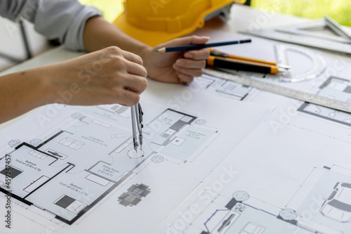 A female architect uses a roundabout to draw on the house designs, she is checking the house plans that she has designed before sending them to the customers, she designs the house and the interior.