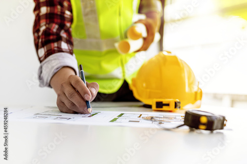 Architect engineer using a pencil to write on the blueprints he has designed, he is checking and revising the drawings before sending the work to the customers. Design and interior design ideas.