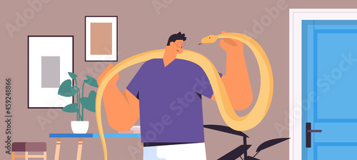 man holding yellow python snake guy having dangerous reptile pet living room interior horizontal