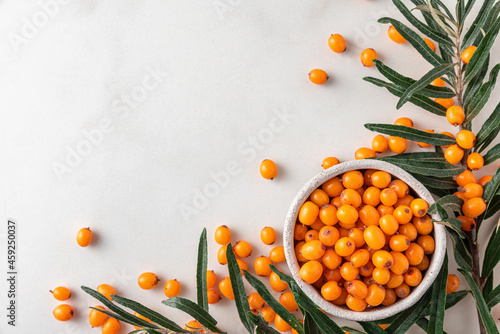 Fresh ripe autumn sea buckthorn berries with leaves on white background. Top view with copy space