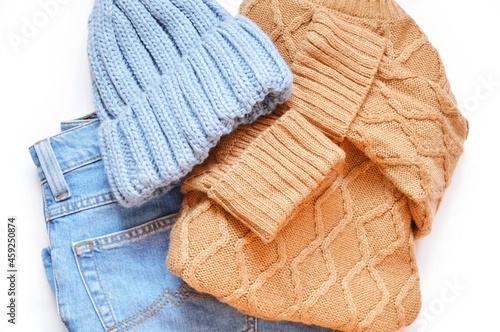 Flat lay fall and winter women's outfit, clothes set. Brown woolen sweater, knitted hat and jeans top view photo