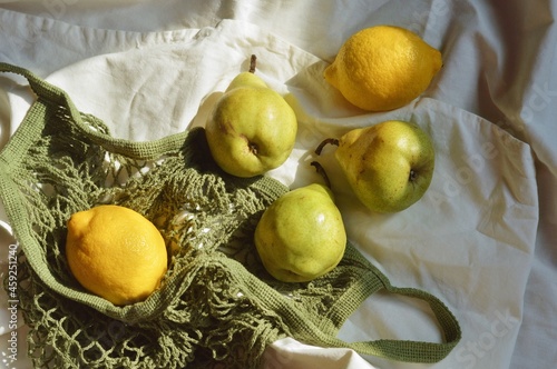 Fototapeta Naklejka Na Ścianę i Meble -  Flat lay photo fresh pears and lemons in a green mesh bag. Healthy food, proper nutrition concept 