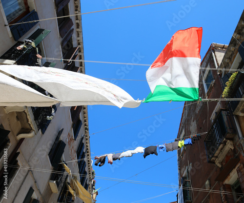 clothes hanging is a large Italian flag in the alley between the houses photo