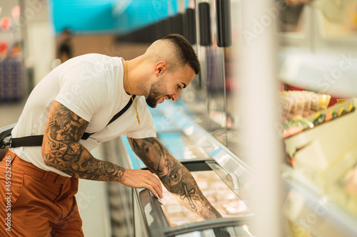 Obraz na plátně Chico atlético fitness tatuado comprando en un supermercado