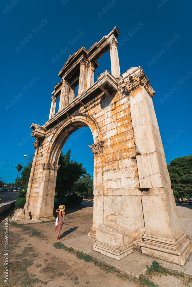 A woman with hat standing under the Arch of Hadrian in Athens, Greece