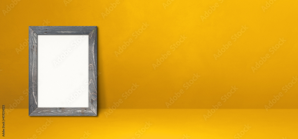 Wooden picture frame leaning on a yellow wall. Horizontal banner Wooden picture frame leaning on a yellow wall. Horizontal banner