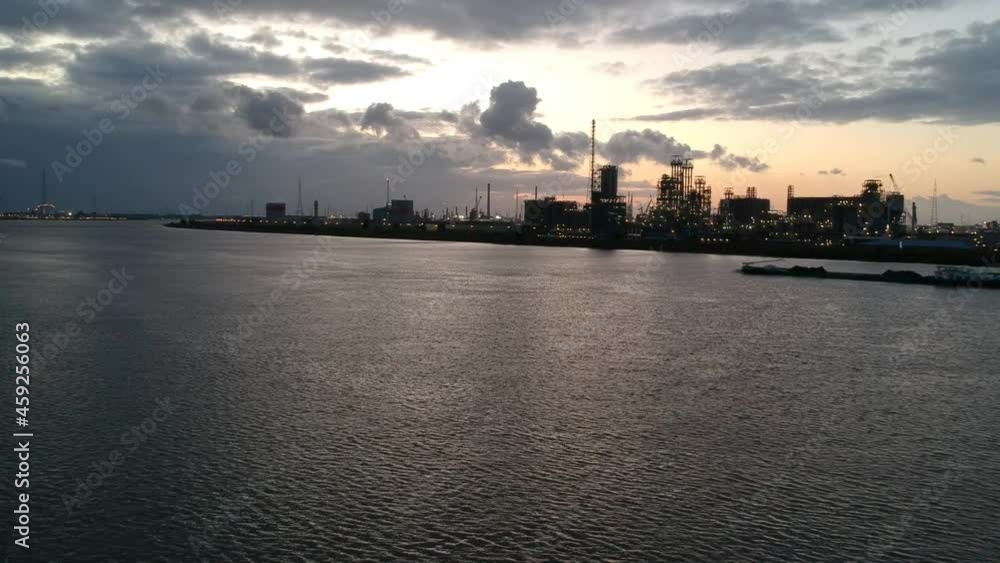 Silhouette of industrial buildings in Antwerp harbor with barge passing by, aerial ascend view Silhouette of industrial buildings in Antwerp harbor with barge passing by, aerial ascend view